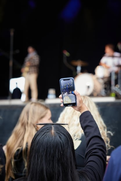 A concert crowd holding up their phones, capturing a special moment during a live music performance. Demonstrates community and engagement.