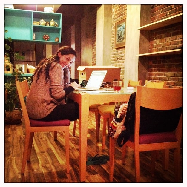 A rock artist sitting at a laptop in a cozy cafe, crafting personalized follow-up emails to contacts made at a music industry event. They're referencing notes from the event and tailoring each message to the individual's interests.