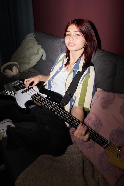 A close-up photo of a young musician intently watching a video interview of a legendary rock guitarist on a tablet. The musician is in a dimly lit practice room, holding their guitar.