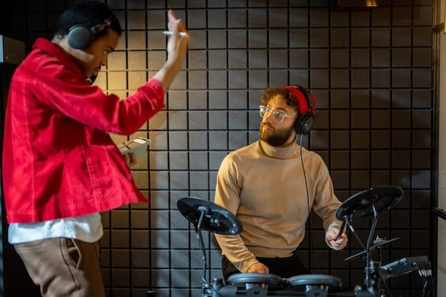 Two rock artists in their 30s engrossed in a recording studio session. Microphones, amps, and instruments fill the room, as one artist passionately explains a concept.