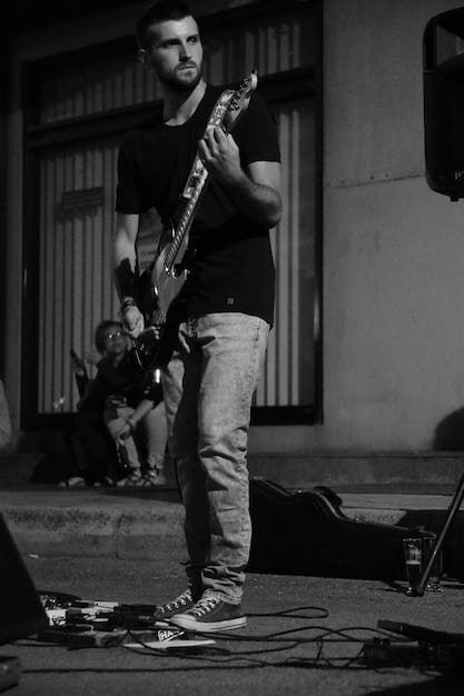 A black and white photograph of a young rock band performing in a small, crowded venue. The band members are intensely focused on their instruments, and the audience is a mix of enthusiastic fans.