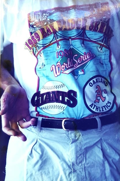 Close-up of a poorly printed band t-shirt with faded colors and misaligned graphics, illustrating the typical signs of counterfeit concert merchandise, with focus on the fabric quality and print details.