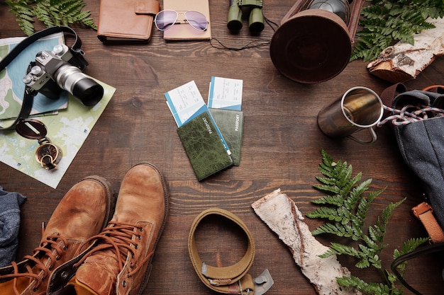 A close-up shot focusing on a well-organized camping packing list. The items are neatly arranged on a tarp or blanket outdoors, including a rolled-up sleeping bag, a small camping stove, a water bottle, sunscreen, a foldable chair, and a headlamp. The scene emphasizes preparedness and the essential gear needed for a comfortable camping experience.