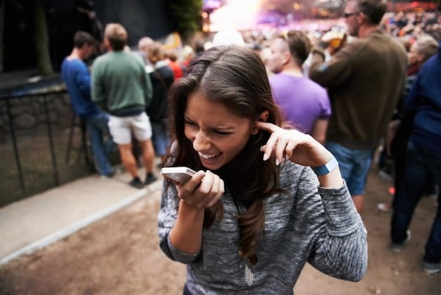 A person holding out a small packet of over-the-counter pain relievers, with a blurred concert crowd in the background, emphasizing the need for quick relief from headaches during a concert.